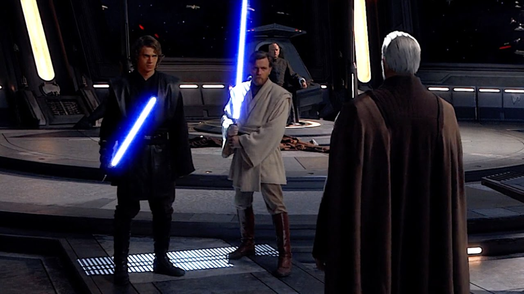 Cena de Star Wars Episódio III: A Vingança dos Sith. Anakin (Hayden Christensen) e Obi-Wan (Ewan McGregor) ligam seus sabres de luz para enfrentar o Conde Dooku (Christopher Lee). Anakin é um homem caucasiano de cabelo castanho escuro, com robes pretos. Obi-Wan é um homem caucasiano de cabelos e barba loiros, usando robes brancos e botas marrons. Anakin segura seu sabre na mão direita, inclinado para o Conde, enquanto Obi-Wan segura o seu com ambas as mãos, junto de seu lado direito. Ambos os sabres são de cor azul, formando um feixe de luz da ponta do cabo até pouco mais de um metro. O Conde Dooku, visto de costas, é um homem caucasiano de cabelos brancos, usando uma capa preta com tons mais claros nas laterais. Atrás de Obi-Wan, podemos ver o Chanceler Palpatine (Ian McDiarmid), um idoso caucasiano de cabelos brancos em uma roupa escura, sentado em um grande trono observando os outros três, com as mãos atadas. Atrás dele, podemos ver uma batalha entre espaçonaves acontecendo, com feixes de luz indo de um lado para o outro. Os personagens se encontram em um grande salão futurista e metálico, com algumas luzes vindo do piso e das laterais.