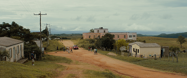 Cena do filme Continente. A imagem é um plano geral de um vilarejo, com uma estrada de terra ao centro e casas pequenas ao redor.