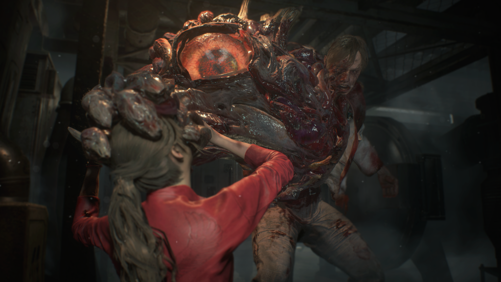 Cena do jogo Resident Evil 2: Claire enfrenta a forma mutante do cientista William Birkin. Claire é uma mulher caucasiana jovem, de cabelos castanhos amarrados num rabo de cavalo, usando uma jaqueta vermelha. William é um homem caucasiano que parece estar sendo consumido por uma massa de carne mutante em seu braço direito, que agarra o rosto de Claire com seus dedos disformes. No que seria seu ombro direito, um grande olho amarelado se abre, encarando a mulher. A massa de carne consome praticamente todo o seu lado direito, enquanto no esquerdo conseguimos ver um homem de cabelos loiros, usando um jaleco de laboratório e calças beges. Os dois estão em uma sala industrial, com grades acima de suas cabeças e tangues e tubos ao seu redor, com uma névoa de vapor começando a se formar atrás deles.