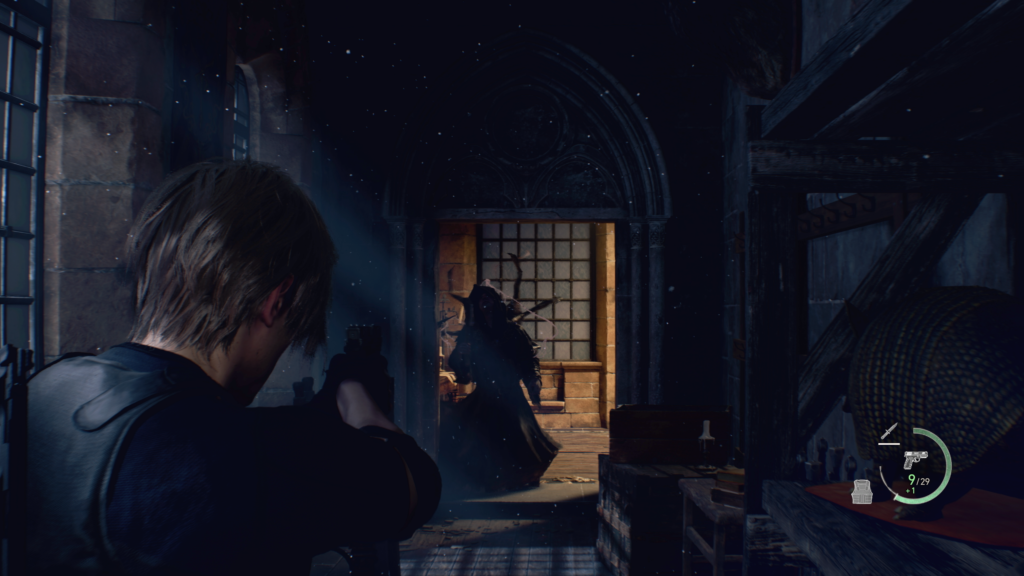 Cena do jogo Resident Evil 4: Leon, no corredor de um castelo, mira em um atacante que parte para cima dele. Leon, à esquerda da tela, é um homem caucasiano de cabelos loiros, usando um colete à prova de balas por cima de uma camiseta preta, segurando uma pistola com ambas as mãos. Uma luz branca vem das janelas do seu lado esquerdo, iluminando o corredor, uma estante e um baú amontoados em sua frente. Na sua frente, um vulto escuro encapuzado cambaleia na sua direção. O vulto usa um robe com saia larga e, em suas costas, vemos as patas de um monstro insectoide guiando seus movimentos. Ele vem de uma sala na frente, iluminada por uma luz laranja que vem do teto. No canto inferior direito há símbolos representando a vida de Leon, numa meia lua verde, a arma que ele tem equipada e a munição disponível, bem como o estado de sua faca e de seu colete à prova de balas.