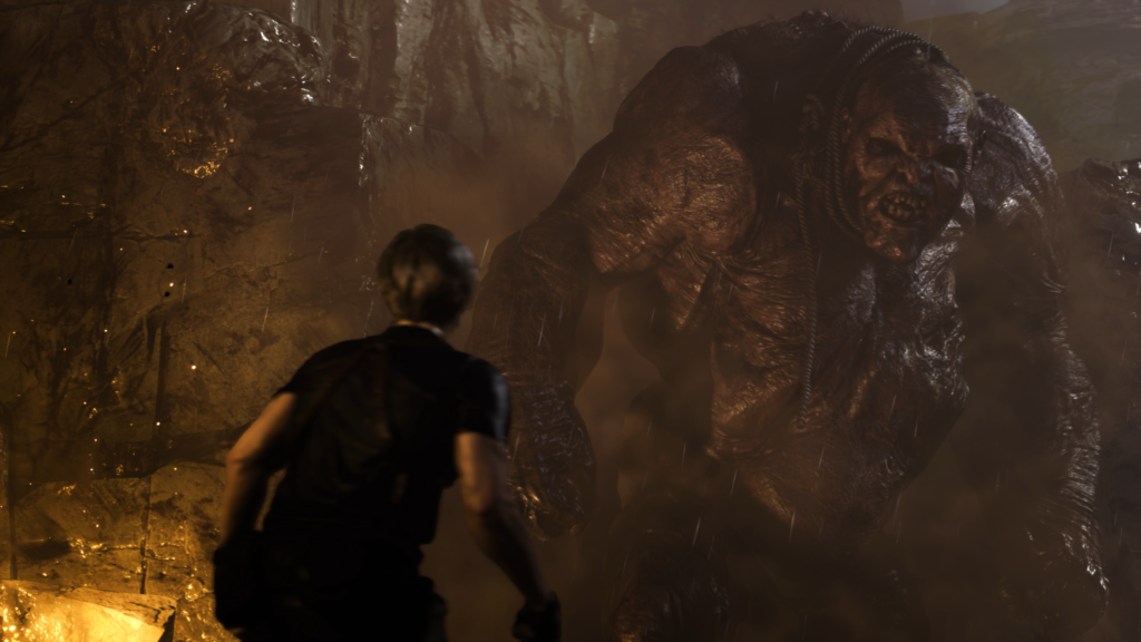 Cena do jogo Resident Evil 4: Leon está de cara à cara com um mutante gigante parecido com um ogro. Leon é um homem caucasiano loiro, usando uma camiseta preta com um coldre de couro nos ombros, fora de foco, à esquerda da tela. À direita, na sua frente, o monstro de pele escura e enrugada arreganha seus dentes. Ele possuí uma corda solta em seu pescoço. Atrás dele, a parede de uma pedreira iluminada por uma chama vindo do canto inferior esquerdo da tela. As fagulhas do fogo se misturam com a chuva que cobre a noite.