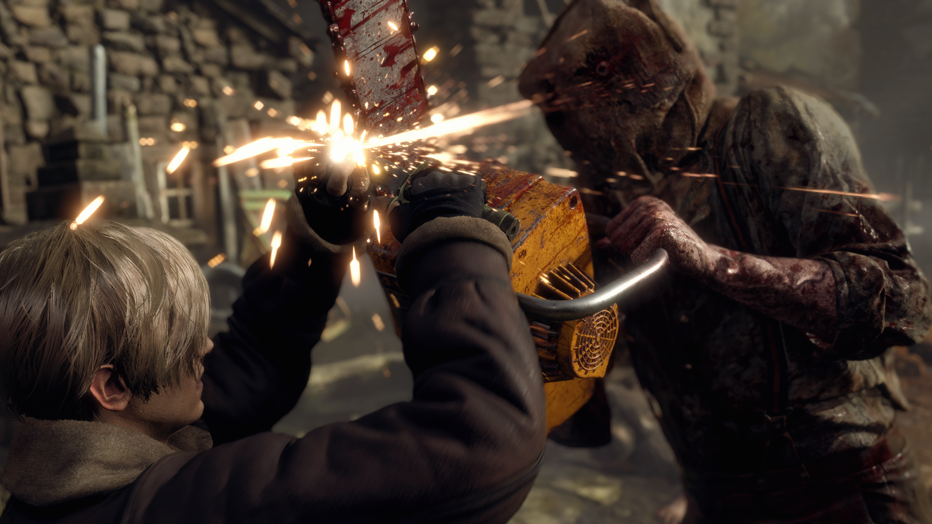 Cena do jogo Resident Evil 4: Leon se defende de uma motosserra com uma faca. Leon é um homem caucasiano loiro, usando uma jaqueta marrom com gola de lã branca e luvas pretas. Ele segura uma faca com a mão direita, aparando o ataque que vem de cima, usando a sua outra mão para suportar a parte chata da lâmina. Na sua frente, um habitante infectado do vilarejo segura uma motosserra amarela apontada para cima, jogando-a contra Leon. Ele usa uma camiseta clara, mas muito suja, com as mangas roladas para cima, com suspensórios escuros por cima. Há um saco bege ocultando seu rosto, com apenas duas aberturas mostrando seus olhos esbugalhados. No ponto em que a motosserra encontra a faca, fagulhas explodem na tela. Atrás deles, vemos casas de pedra de um vilarejo iluminadas pela luz do sol, com tábuas de madeira empilhadas ao lado das paredes, fora de foco.