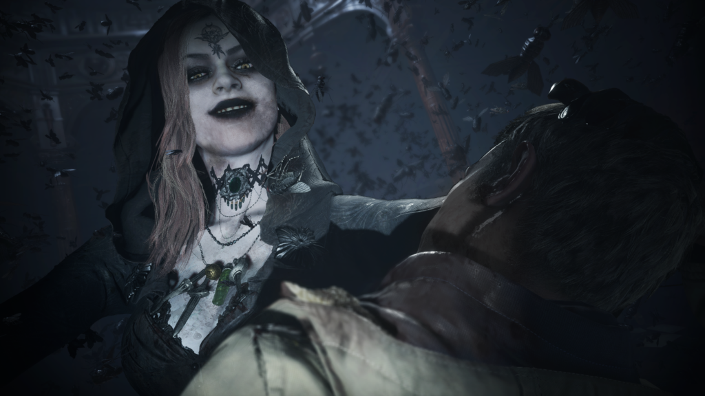 Cena do jogo Resident Evil: Village. O protagonista é atacado por uma mulher pálida de cabelos loiros, coberta por um capuz preto e roupas da mesma cor. Ela, à esquerda da tela, usa uma gargantilha elaborada preta e um colar com joias diversas no pescoço. Seus olhos tem írises amarelas  Ethan, um homem caucasiano e loiro, usa um casaco bege por cima de uma blusa escura, e a mão esquerda da mulher empurra sua cabeça para o lado. Um enxame de insetos voa ao redor deles, que se encontram numa sala grande e decorada por sustentações de madeira escura, com uma luz branca vindo do teto.