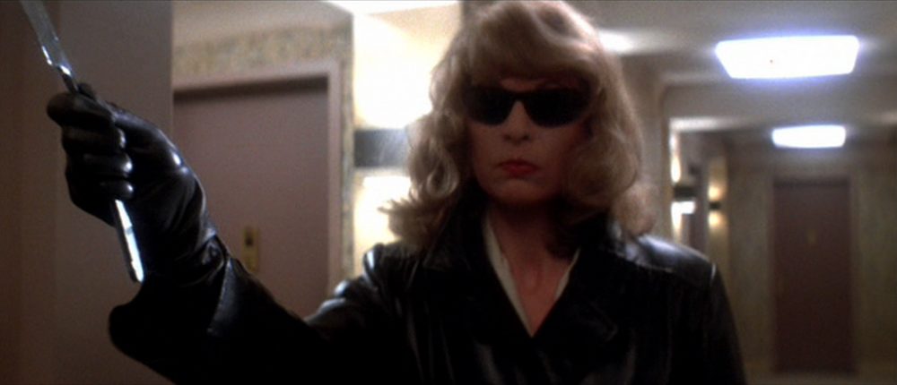 Fotografia da personagem Bobbi. A imagem mostra Bobbi de óculos escuros, com uma expressão facial neutra e erguendo uma navalha com a mão direita.