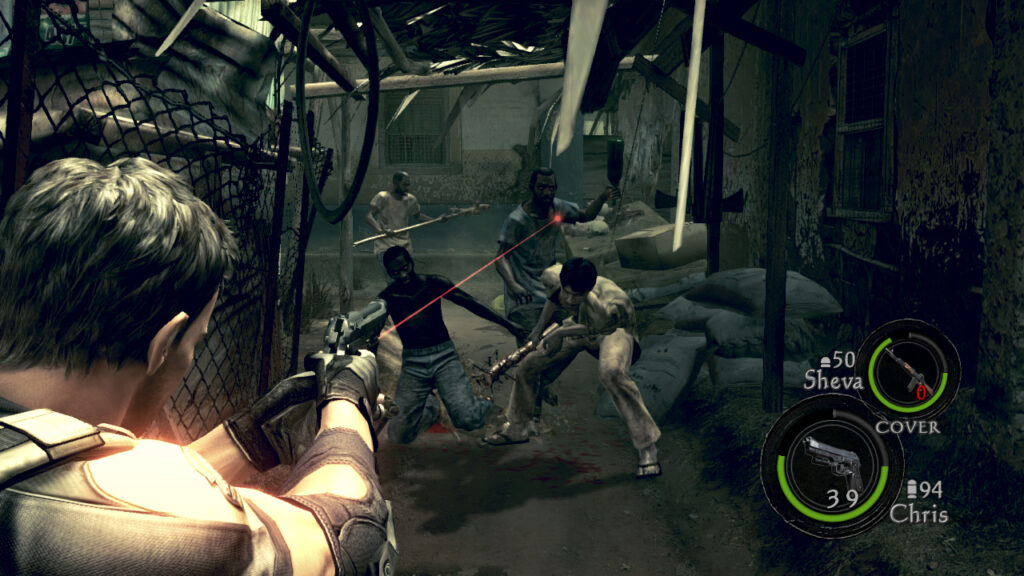 Cena do jogo Resident Evil 5. Jogamos com Chris enquanto ele mira num grupo de infectados que se aproxima dele. Chris é um homem caucasiano de cabelos pretos e curtos, segurando uma pistola com mira laser no canto esquerdo da tela. No canto inferior direito, dois círculos informam a munição disponível para a arma e a vida de Chris, assim como a de sua parceira, Sheva, num círculo acima. O grupo de infectados na frente dele segura armas rudimentares como porretes com pregos e garrafas vazias. À esquerda, um deles se ajoelha após ser acertado nas pernas. Chris mira no que está no meio dos três, se preparando para jogar uma garrafa. Atrás deles, um quarto infectado se aproxima, segurando o que parece ser um poste de madeira. Eles estão num corredor estreito, com uma grade coberta por entulho na esquerda e uma parede de concreto encardida na direita com sacas de grãos empilhadas nos lados. Atrás dos infectados, vemos outra casa com as janelas fechadas. A luz do Sol é bloqueada parcialmente por algumas partes do teto dilapidado.