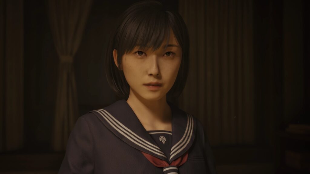 Cena do jogo Silent Hill f. Hinako olha confusa para frente. Ela é uma garota japonesa de cabelos negros e curtos, usando um uniforme azul marinho com linhas brancas nas abas e um lenço vermelho por baixo delas. Atrás delas vemos cortinas brancas na frente de paredes de madeira. A cena é iluminada por luzes quentes vindas de frente da câmera.