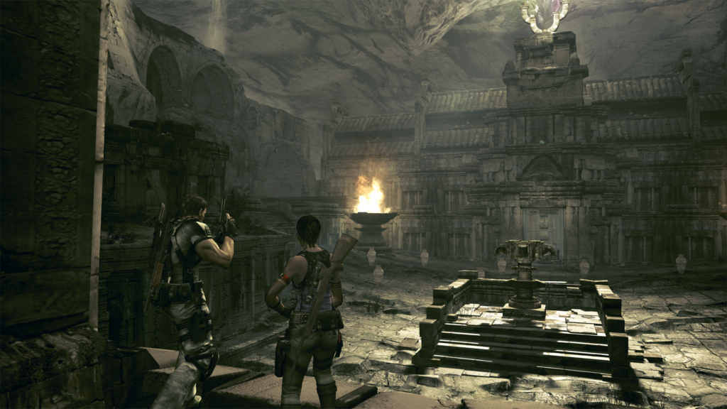 Cena do jogo Resident Evil 5. Chris (à direita) e Sheva (à esquerda) chegam até o salão principal de um templo em ruínas dentro de uma caverna. No centro do tablado na frente deles há uma plataforma com escadas dando para um mecanismo circular. Atrás dessa plataforma há uma grande porta dando para uma parte mais interior da construção, com vasos espalhados na sua frente. No teto acima deles, um cristal reflete a luz solar que entra por uma abertura no teto. Uma grande pira acesa na extremidade esquerda do tablado também ilumina o cenário. Chris é um homem caucasiano de cabelos pretos, segurando uma pistola apontada para cima com ambas as mãos, usando uma calça bege e uma camiseta clara. Em suas costas podemos ver outros armamentos. Sheva é uma mulher negra de cabelos escuros, usando uma calça verde e uma camiseta regata roxa com adornos nos braços e com um rifle longo nas costas.
